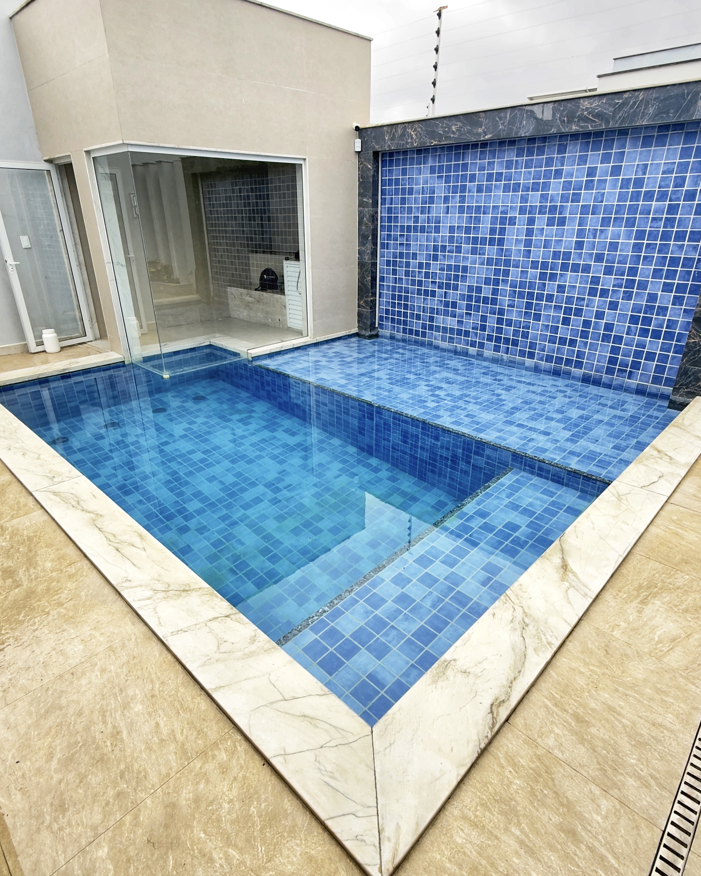 Piscina de alvenaria revestida em pastilha azul com cascata e spa — alto padrão